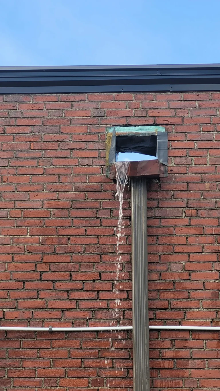 Staining on a brick wall below a rainwater hopper